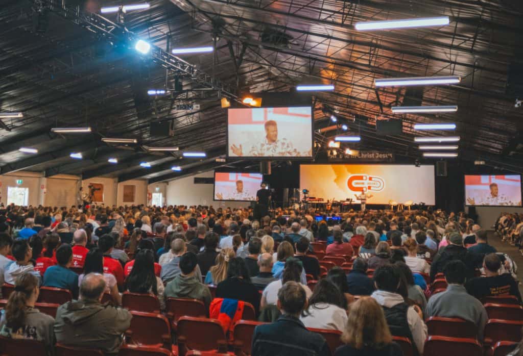 Audience attending Katoomba Easter Convention with stage and screens in the background.